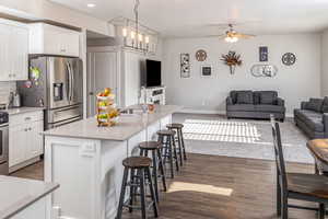 Kitchen with a center island with sink, white cabinets, decorative light fixtures, and sink