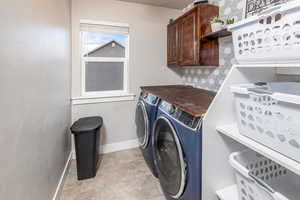 Washroom featuring cabinets, light tile patterned floors, and washer and dryer