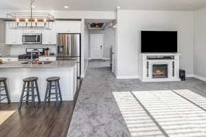 Kitchen with stainless steel appliances, white cabinetry, a breakfast bar area, and sink