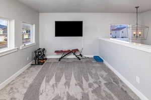 Interior space with a textured ceiling, carpet floors, and a notable chandelier