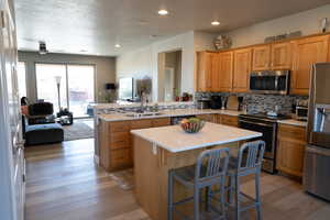 Kitchen featuring sink, a center island, stainless steel appliances, kitchen peninsula, and light wood-type flooring