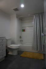 Bathroom featuring shower / bathtub combination with curtain and toilet