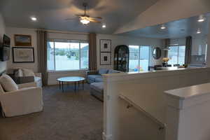 Carpeted living room featuring ceiling fan and lofted ceiling