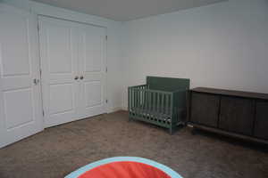 Unfurnished bedroom with a closet, carpet, and a nursery area