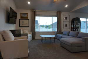 Carpeted living room featuring ceiling fan and lofted ceiling