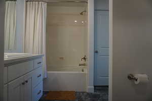 Bathroom featuring vanity and shower / bathtub combination with curtain