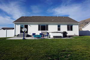 Back of house featuring a lawn, central air condition unit, a patio, and a hot tub