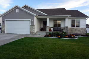 Craftsman-style home featuring covered porch, a garage, and a front lawn