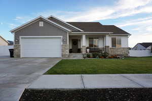 Craftsman inspired home featuring covered porch, a garage, and a front lawn