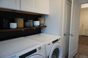 Washroom with washer and clothes dryer, cabinets, and dark hardwood / wood-style floors