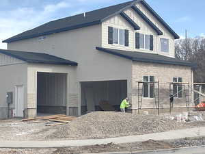 Exterior space with an attached garage, board and batten siding, a shingled roof, and stone siding