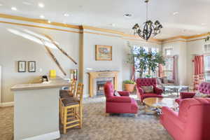 Living room featuring a fireplace, light colored carpet, a chandelier, and ornamental molding