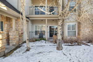 Snow covered property entrance with a balcony