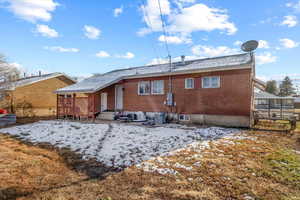 Snow covered back of property featuring central AC