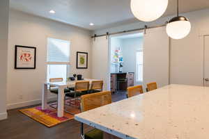 Dining room with a barn door and dark wood-type flooring