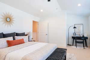 Bedroom with light colored carpet and vaulted ceiling