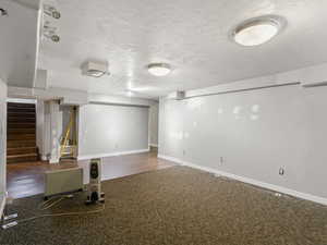 Basement with a textured ceiling and dark hardwood / wood-style floors