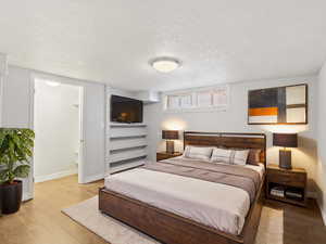 Bedroom with light hardwood / wood-style flooring and a textured ceiling