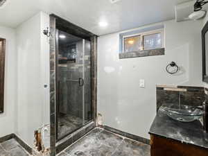 Bathroom featuring vanity, a shower with door, and a textured ceiling