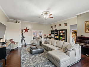 Living room featuring dark hardwood / wood-style floors, ceiling fan, ornamental molding, and french doors