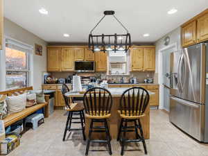 Kitchen with decorative light fixtures, a center island, stainless steel appliances, and light tile patterned flooring