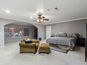 Carpeted bedroom with ceiling fan, a textured ceiling, and ornamental molding