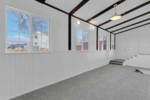 Empty room featuring a wealth of natural light, a mountain view, carpet floors, and lofted ceiling with beams