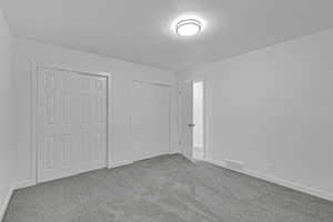 Unfurnished bedroom featuring carpet floors and two closets