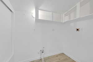 Laundry area with hookup for a washing machine, light wood-type flooring, a textured ceiling, gas dryer hookup, and electric dryer hookup