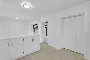 Interior space with a textured ceiling, light wood-type flooring, and wood walls