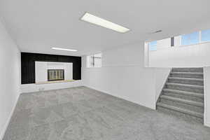 Basement with wooden walls, a fireplace, and carpet floors