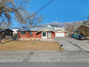 Ranch-style home with a mountain view, a front yard, and a garage