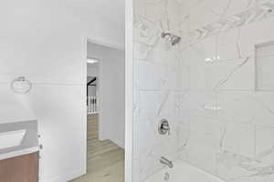 Bathroom with vanity, wood-type flooring, and tiled shower / bath