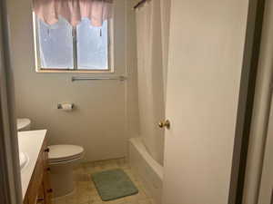 Full bathroom with tile patterned floors, vanity, toilet, and shower / bathtub combination with curtain