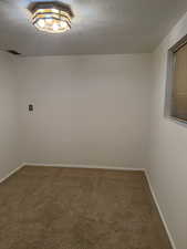 Carpeted empty room with visible vents, baseboards, and a textured ceiling