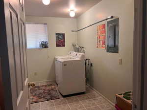 Laundry room featuring electric panel, light tile patterned flooring, washer and dryer, and a textured ceiling