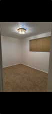 Carpeted empty room featuring baseboards and a textured ceiling