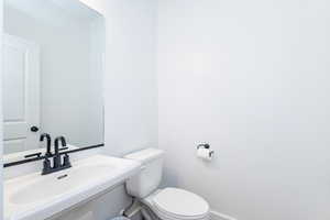 Half Bath with sink and toilet. Located off the kitchen next to garage door.