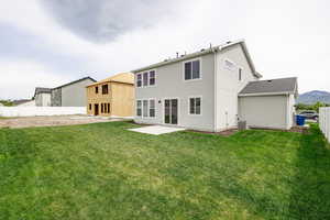 Back of house featuring a mountain view, cooling unit, a patio area, and a lawn