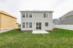 Rear view of house featuring a lawn, a mountain view, and a patio