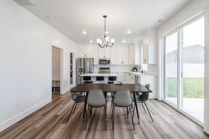 Dining area with sink, plenty of natural light, a notable dining chandelier, and medium wood-type flooring