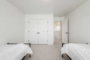 Bedroom featuring light carpet and a closet