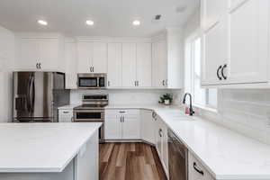 Kitchen featuring white cabinets, sink, appliances with stainless steel finishes, and tasteful backsplash