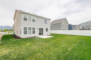 Back of house featuring a mountain view, a yard, and a patio area