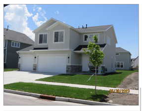 View of front of house with a front yard and a 3 car garage