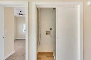 Laundry area with hookup for an electric dryer, hookup for a washing machine, light wood-type flooring, and ceiling fan