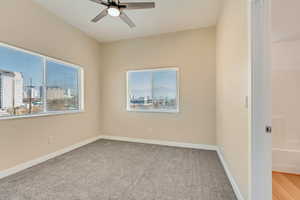 Unfurnished room with light carpet, a wealth of natural light, and ceiling fan