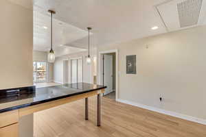 Kitchen featuring a textured ceiling, electric panel, light hardwood / wood-style flooring, and decorative light fixtures