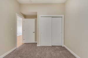 Unfurnished bedroom with light carpet and a closet