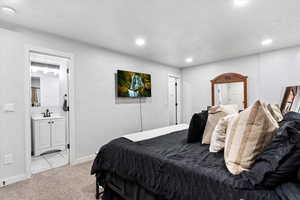 Bedroom featuring light colored carpet, sink, and connected bathroom